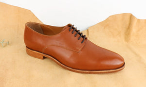 Brown leather Derby shoe on a beige fabric background, example from the VALEVRO shoemaking course