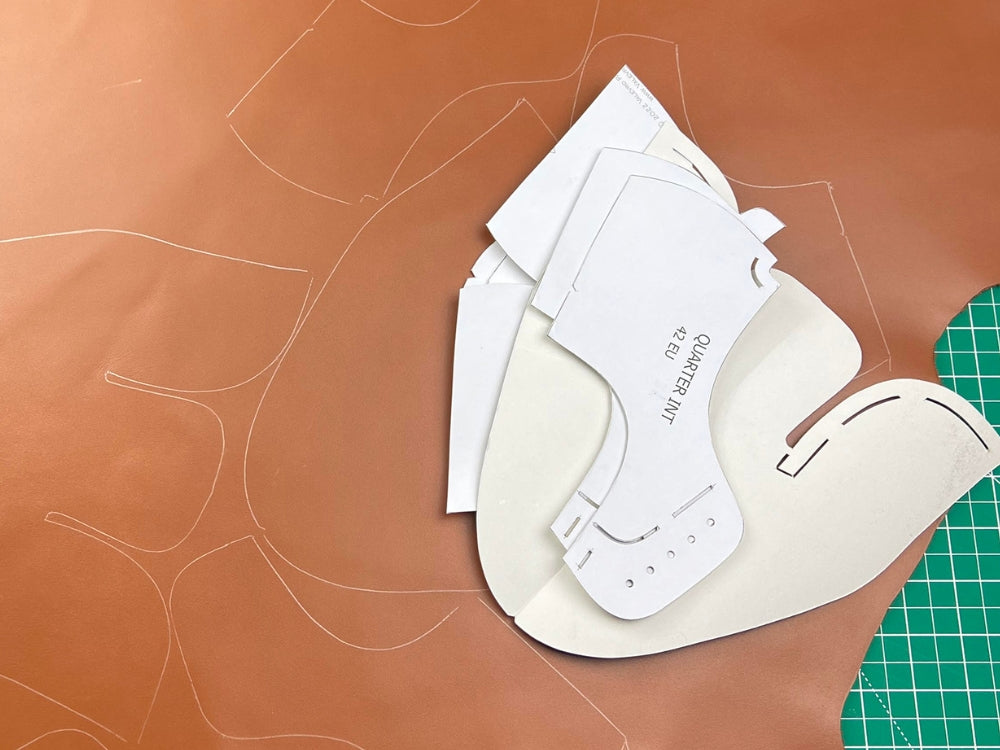Leather cutting template on a brown leather surface with a green cutting mat. Process is part of the VALEVRO online shoemaking course.