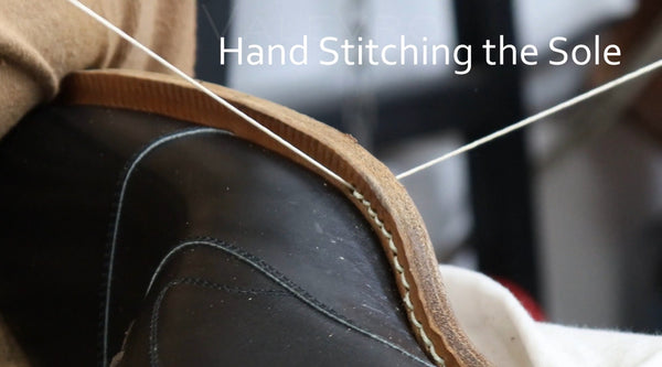 Close-up of a black leather shoe sole being hand-stitched with white thread, overlaid with the text 'Hand Stitching the Sole'.