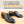 A pair of black leather cap-toe oxford shoes with a polished finish, displayed on a light beige surface below a text banner that reads 'VIDEO COURSE GOODYEAR WELTED CONSTRUCTION HAND WELTED TECHNIQUE'.