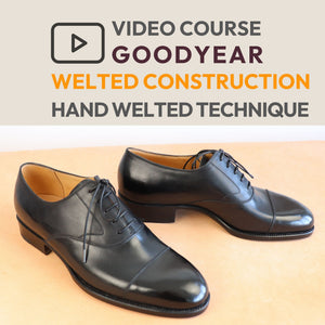 A pair of black leather cap-toe oxford shoes with a polished finish, displayed on a light beige surface below a text banner that reads 'VIDEO COURSE GOODYEAR WELTED CONSTRUCTION HAND WELTED TECHNIQUE'.